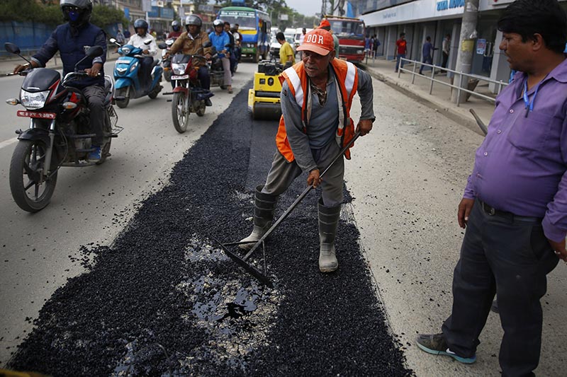 Workers of Department of Roads blacktopping a road dug up for laying Melamchi drinking water project pipelines at Thapathali, Kathmandu, on Thursday, July 20, 2017. Photo: tHT