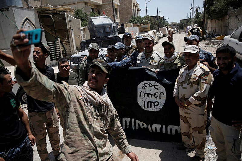 Members of the Iraqi Army's 9th Armoured Division are photographed with an Islamic State flag, claimed after fighting with Islamic State militants in western Mosul, Iraq, on June 17, 2017. Photo: Reuters/ File