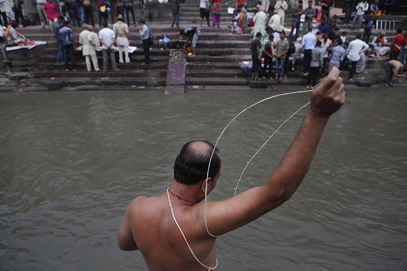 A devout Nepali Hindu man performs a ritual during the Janai Purnima festival at Pashupati temple in Kathmandu, Nepal, Friday, July 28, 2017. Janai Purnima or the annual Sacred Thread Festival marks the day when the devout Hindu males change the white cotton thread they wear across their torsos and take a ritual bath in a river or a pond. The sacred thread, when it first tied, indicates formal entry into adulthood and a promise to follow their Hindu faith. Photo: AP
