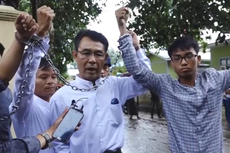 (left to right), Burmese journalists La Wei, from the Irrawaddy, Aye Nai, from the Democratic Voice of Burma, and Pyi Phone Aung, from the Democratic Voice of Burma raise their chained wrists decrying the lack of freedom and democracy as they leave the court after facing charges of unlawful association,  in Hsipaw, Shan state, Myanmar, on Tuesday, July 18, 2017. Photo: Democratic Voice of Burma via AP