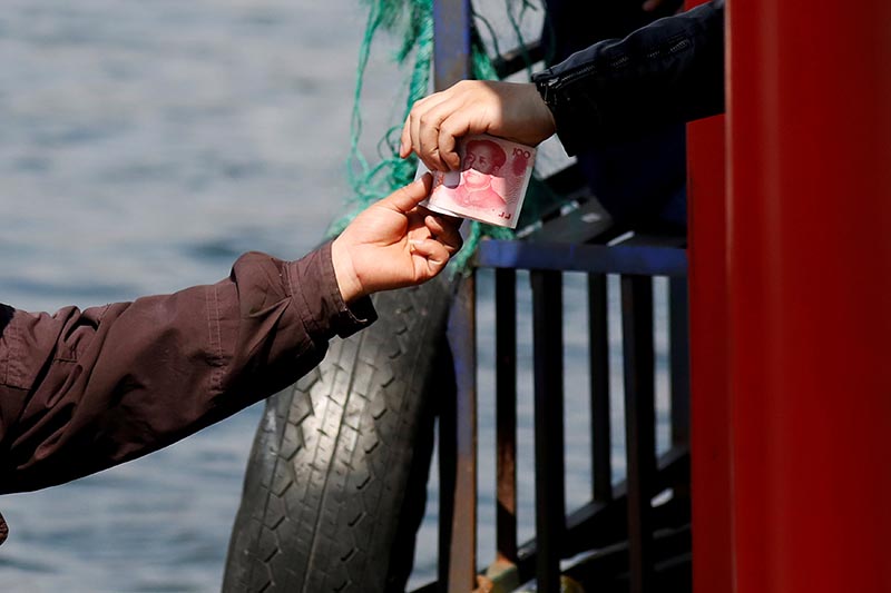 A vendor receives Chinese banknotes after selling North Korean goods to tourists on a boat taking them from the Chinese side of the Yalu river for sightseeing close to the shores of North Korea near Dandong in China's Liaoning Province, on April 1, 2017. Photo: Reuters/ File