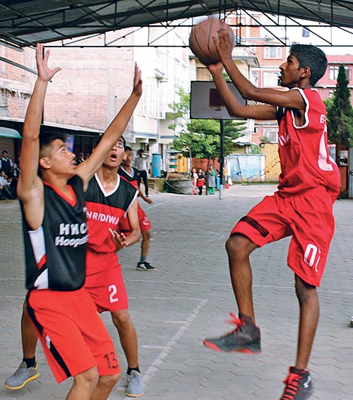 A player of Shridiwa Jumps for a basket under pressure from HHCA players during their 11th Shridiwa Monsoon Meet Inter-school Basketball Tournament match in Kathmandu, on Sunday. Photo: THT
