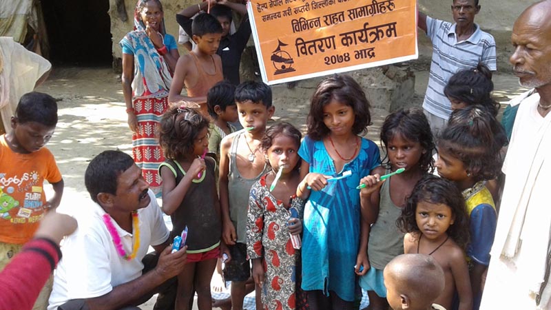 Surya Narayan Yadav (left), an engineer at the DHWC distributes toothpaste and toothbrush to the children in Krishnanagar Musahar settlement of Rajbiraj Municipality-9 of Saptari district, on Monday, August 28, 2017. Photo: Byas Shankar Upadhyay