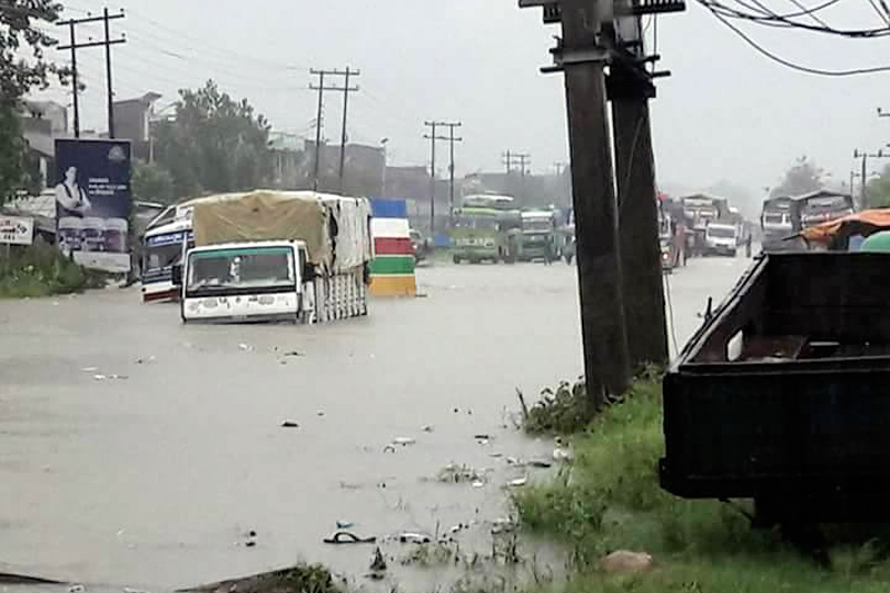Trucks are seen half submerged while parked alongside a road, along the East-West Highway, in Bara, on Saturday, August 12, 2017. Photo: Pushpa Raj Khatiwada
