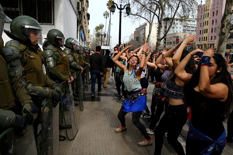 Demonstrators perform a dance in front of riot policemen during a march called by students to request changes in the education system in Santiago, Chile, on September 5, 2017. Photo: Reuters