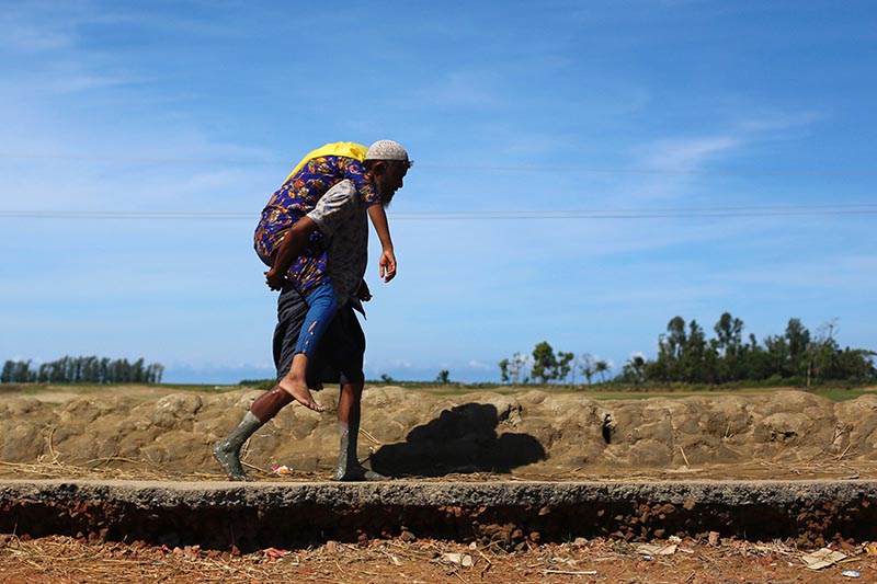 A Rohingya refugee man carries a woman after crossing the Bangladesh-Myanmar border by boat through the Bay of Bengal in Shah Porir Dwip, Bangladesh, on September 15, 2017. Photo: Reuters