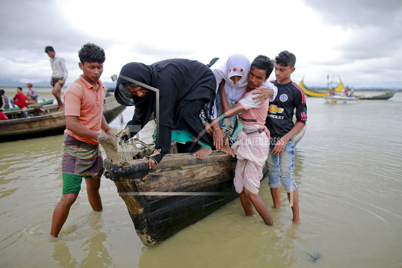 Bangladeshi villagers help two elderly Rohingya women get down from a boat after crossing a canal at Shah Porir Deep, in Teknak, Bangladesh, Thursday, Aug. 31, 2017. Photo: AP