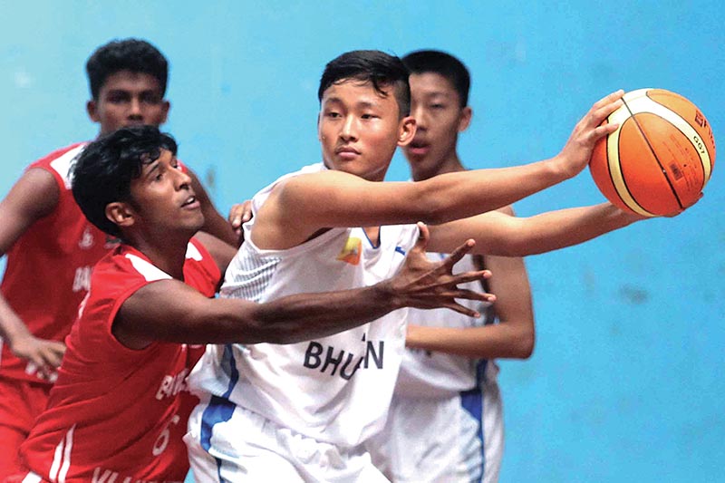 Tshering Penjor (right) of Bhutan looks  for his teammate to pass the ball under pressuer from Tutul Kumar Biswas of Bangladesh during their U-16 SABA basketball Championship match at the NSC covered hall, in Kathmandu, on Tuesday. Photo: THT