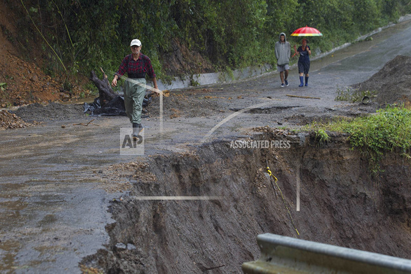 Neighbors walk under the rain past a washed out road in Alajuelita on the outskirts of San Jose, Costa Rica, Thursday, Oct. 5, 2017. Photo: AP