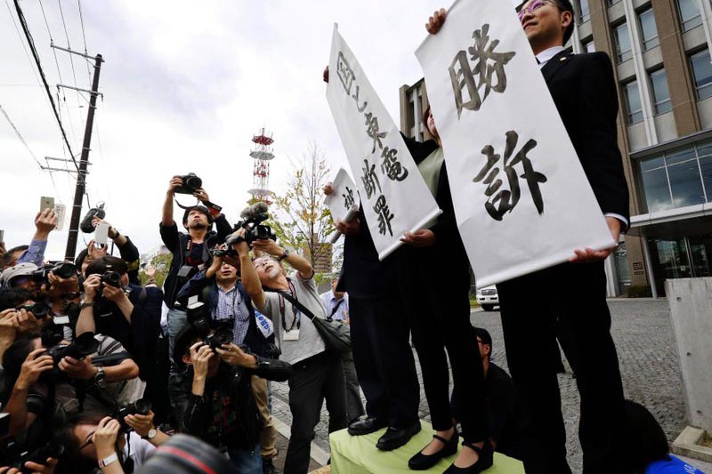 Lawyers show banners reading u201cVictoryu201d following the verdict, outside the Fukushima District Court in Fukushima, eastern Japan, on Tuesday, October 10, 2017. Photo: AP