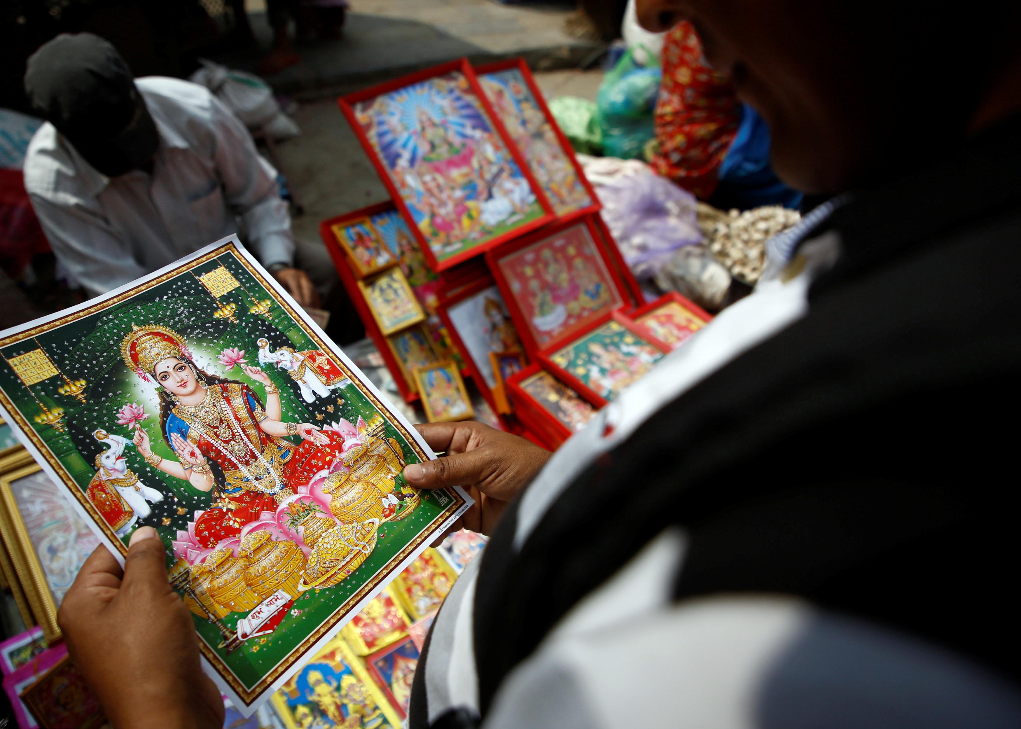 A man selects a poster of Goddess of Wealth Laxmi before buying it for the Tihar festival, also called Diwali, in Kathmandu, October 15, 2017. Photo: Reuters