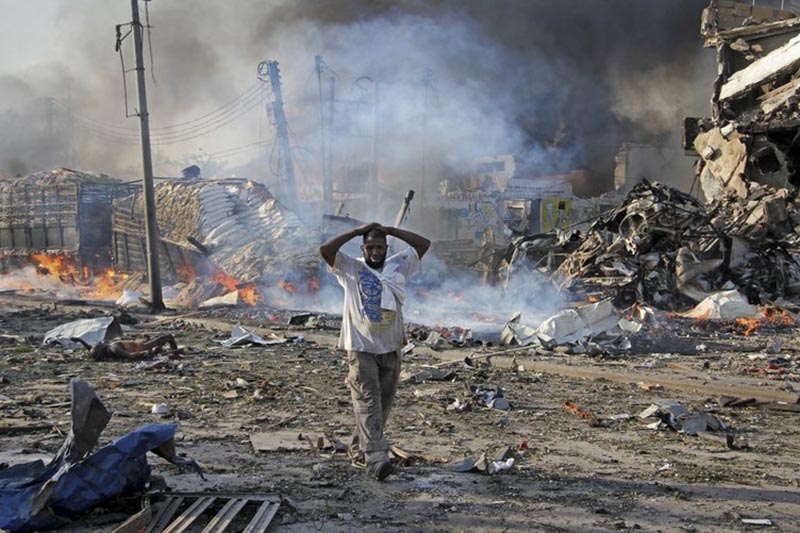 A Somali gestures as he walks past a dead body, left, and destroyed buildings at the scene of a blast in the capital Mogadishu, Somalia, on Saturday, October 14, 2017. Photo: AP