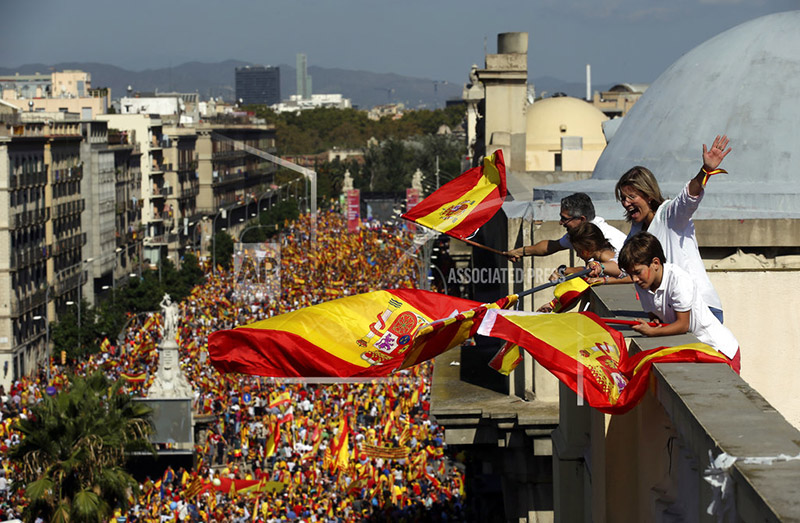 People on a rooftop wave Spanish flags during a march in downtown Barcelona, Spain, to protest the Catalan government's push for secession from the rest of Spain, Sunday Oct. 8, 2017. Photo: AP
