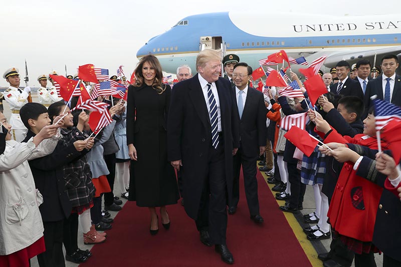 Children wave US and Chinese flags as US President Donald Trump and first lady Melania Trump arrive at Beijing Airport, in Beijing, on Wednesday, November 8, 2017. Photo: Pang Xinglei/Xinhua via AP