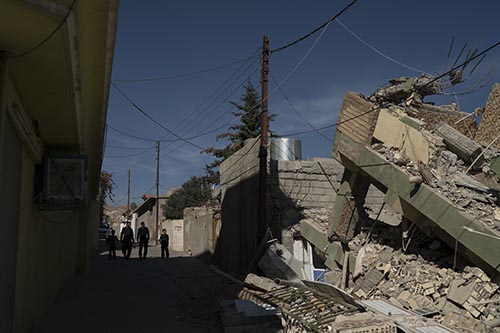 People walk next to a destroyed house after an earthquake at the city of Darbandikhan, northern Iraq,on  Monday, November 13, 2017. Photo: AP