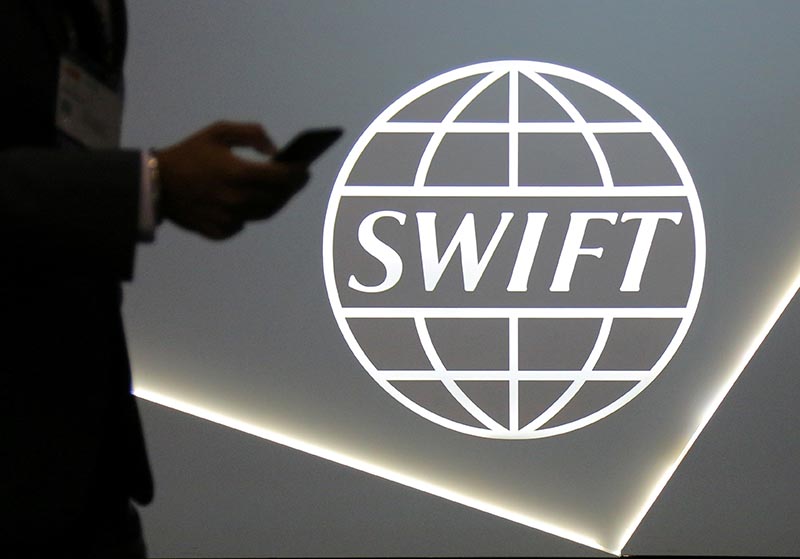 A man using a mobile phone passes the logo of global secure financial messaging services cooperative SWIFT at the SIBOS banking and financial conference in Toronto, Ontario, Canada, on October 19, 2017. Photo: Reuters