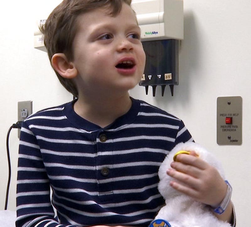 In this undated photo made from video, 5-year-old cancer patient Alex Bridges speaks to a nurse and being comforted by robotic duck just before treatment at medical facility in Atlanta. A plush, robotic duck may soon become a fixture in the world of children who have cancer. The social robot can be silly, happy, angry, scared or sick just like them, and help them cope creatively with their illness through the power of play. (AP Photo/Marina Hutchinson)
