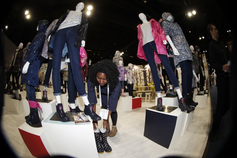 In this photo taken with a fisheye lens, Ashley Winters, of New York City, places a pair of boots amid the mannequins on display in the Joules clothing display at the opening of the Outdoor Retailers and Snow Show in the Colorado Convention Center, Thursday, Jan. 25, 2018, in Denver. Three floors of all the latest products for outdoor use makes the event the largest U.S. trade show for the outdoor and winter sports industries that represent $887 billion in sales