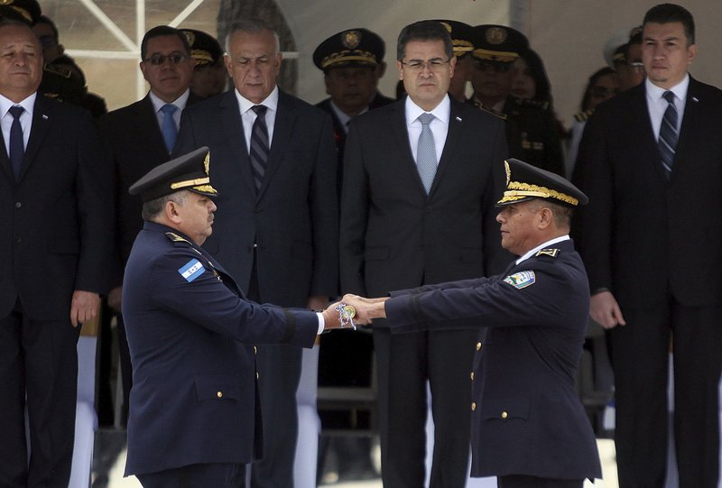 Honduran President Juan Orlando Hernandez, behind second from right, watches the change of command exchange ceremony between his new National Police Chief Jose David Aguilar Moran, left, and outgoing Gen. Felix Villanueva in Tegucigalpa, Honduras. A confidential government report obtained by the Associated Press alleges that Aguilar helped a cartel leader pull off the delivery of nearly a ton of cocaine, raising questions about Hondurasu2019 much-touted purge of corrupt police and the reliability of the administration of Hernandez, a key U.S. ally in the war on drugs