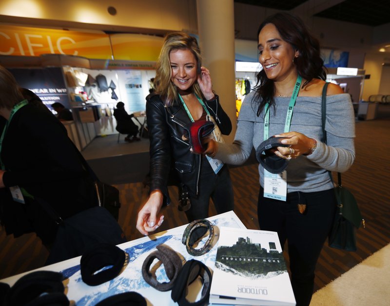 Reina Govindarajan, right, and Brenna Griffiths, both of Los Angeles, try on ear muffs at the booth of a company named 180s at the Outdoor Retailer and Snow Show in the Colorado Convention Center Friday, Jan. 26, 2018, in Denver. Sales of outdoor equipment are slipping as millennials drive changes in U.S. consumer habits by favoring clothes and sporting goods that are less specialized and more versatile, analysts say.