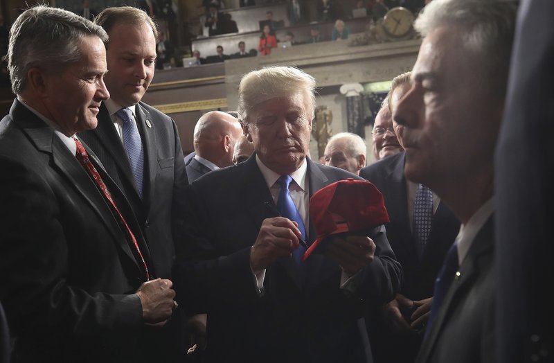 President Donald Trump signs a hat after finishing the State of the Union address in the chamber of the U.S. House of Representatives Tuesday, January 30, 2018. Photo: AP