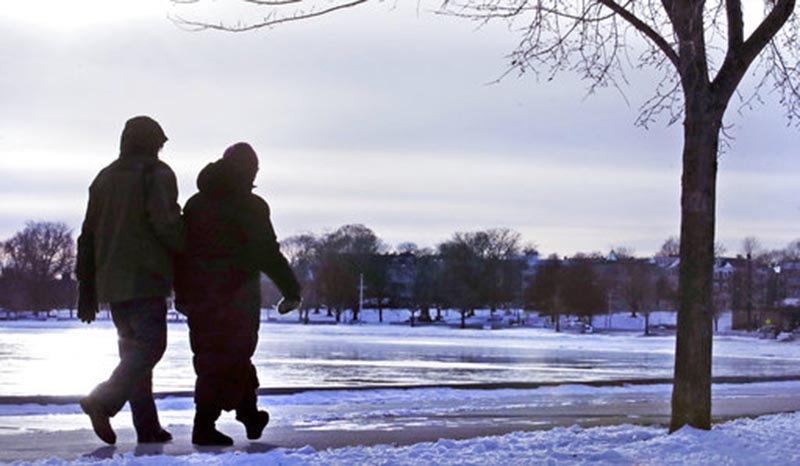A couple bundled in winter clothing walk along the frozen shore in the South Boston neighborhood of Castle Island, Tuesday, Jan. 2, 2018. Bitterly cold temperatures gripped a large swath of the nation, testing the mettle of even winter-wise northerners and delivering a shock to those accustomed to far milder weather in the South.