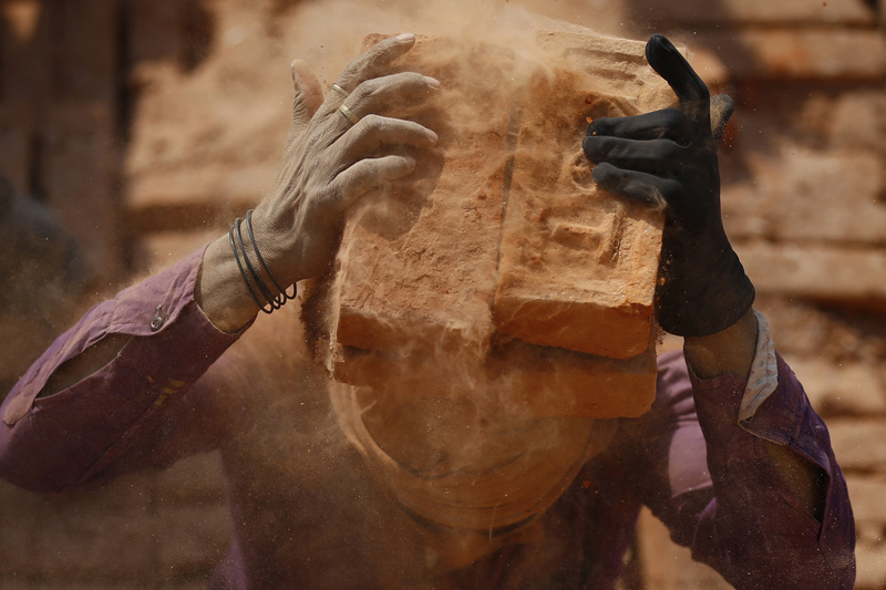 A migrant labourer stacks burnt bricks on his head at a brick kiln in Bhaktapur, on Thursday, January 11, 2018. Photo: Skanda Gautam