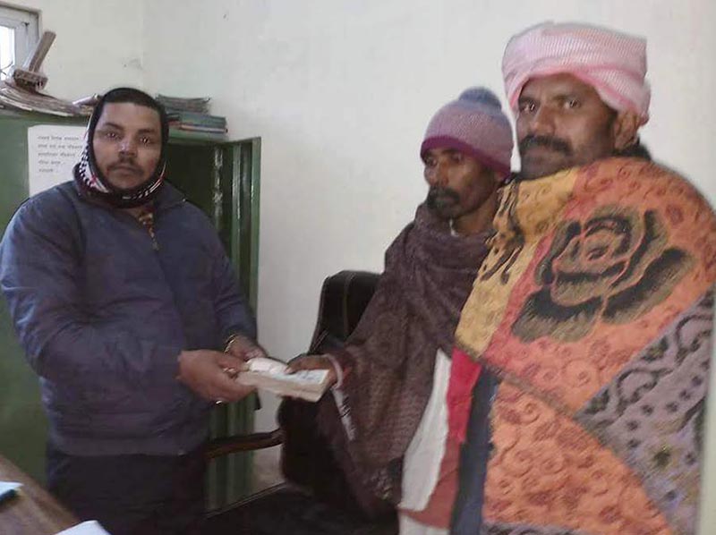 A government official handing over relief cash to families that lost their members to cold, at the district administration office, Rautahat, on Wednesday, January 17, 2018. Photo: THT