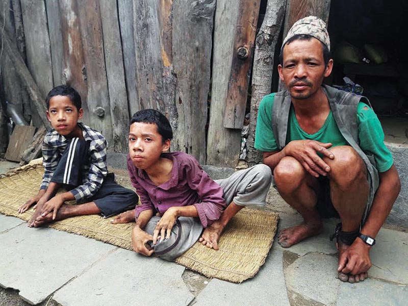 A man along with his two disabled sons sitting outside his house, in Gaurishankar Rural Municipality, Dolakha, on Saturday. Photo: THT