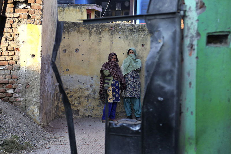 Indian women look through the gate of a house damaged allegedly due to firing from the Pakistan side of the border at Korotana village, in Ranbir Singh Pura district of Jammu and Kashmir, India, Friday, Jan.19,2018. Photo: AP