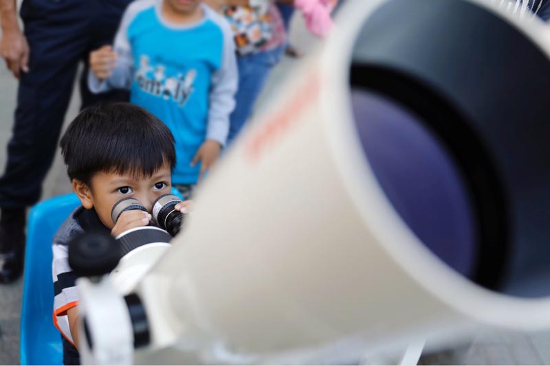 A boy looks through a telescope set up by astronomers before the start of a lunar eclipse in Jakarta, Indonesia January 31, 2018. Photo: Reuters