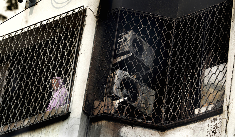 A woman looks out from the window of a residential building after it was partially damaged in an early morning fire which claimed lives in Mumbai, India, Thursday, January 4, 2018. Photo: AP