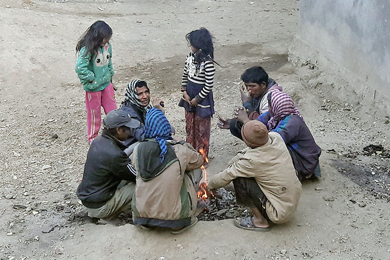 People sit around fire to keep themselves warm, as temperature dips sharply, at Martardi, in Bajura district, on Monday, January 08, 2018. Photo: Prakash Singh