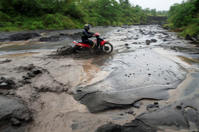 A motorcycle driver crosses a river with lahar flow coming from Mount Mayon volcano in Daraga, Albay province, south of Manila, Philippines January 27, 2018. Photo: REUTERS
