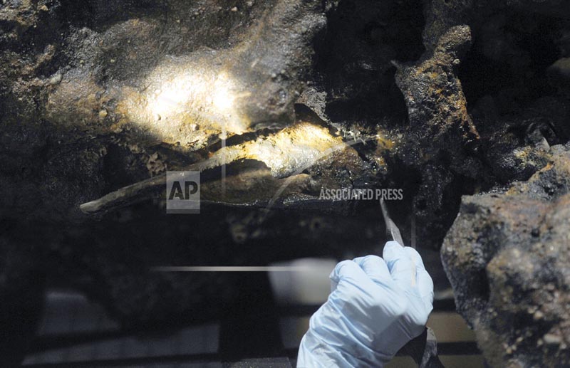 In this August 14, 2017 photo, Marie Kesten Zahn, an archaeologist and education coordinator at the Whydah Pirate Museum in West Yarmouth, Mass., probes the concretion surrounding a leg bone that was salvaged from the Whydah shipwreck off the coast of Wellfleet on Cape Cod. Photo: AP