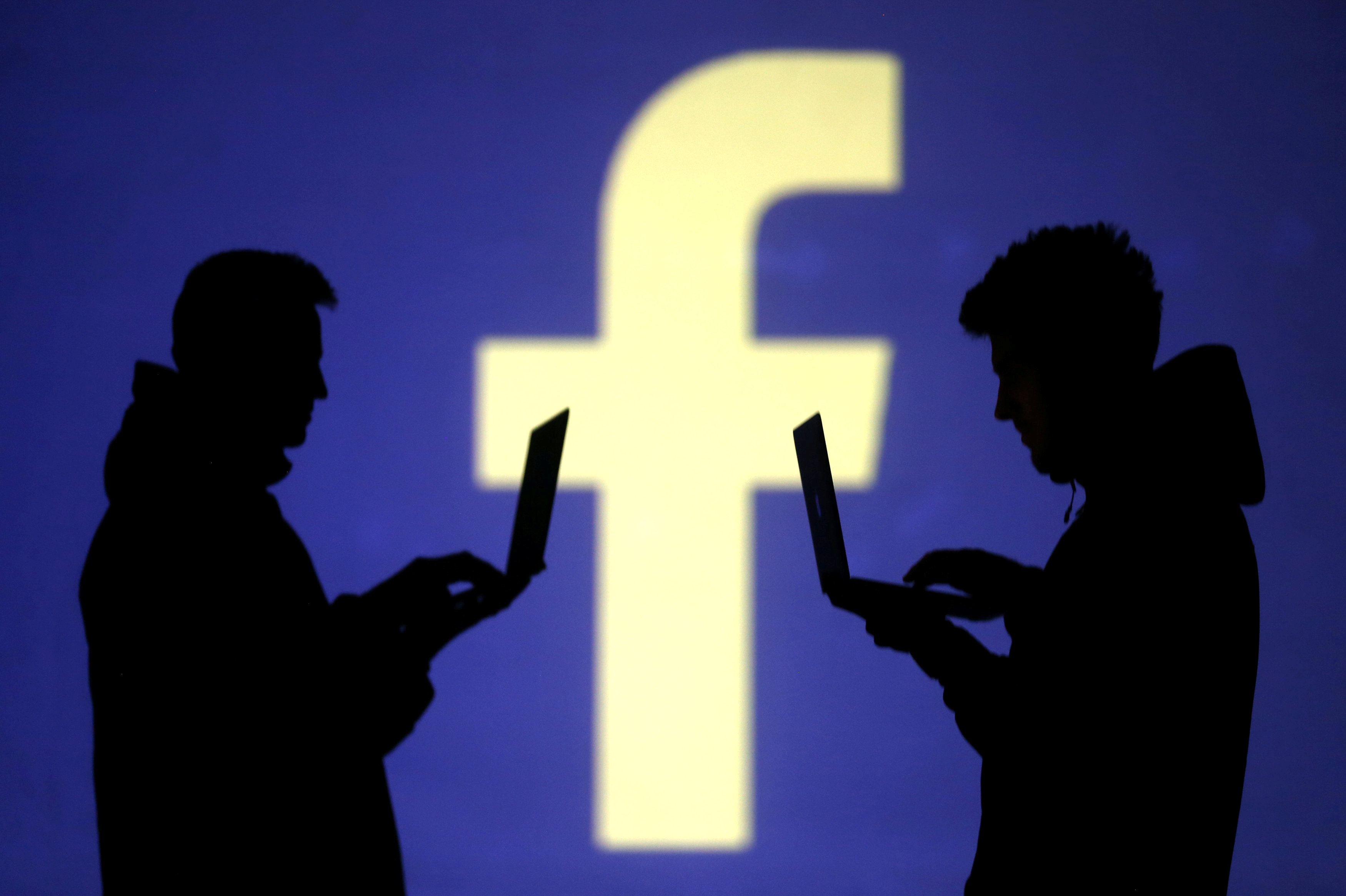 FILE - Silhouettes of laptop users are seen next to a screen projection of Facebook logo in this picture illustration taken March 28, 2018. Photo: Reuters
