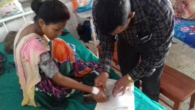Radha Chaudhary, the victim who was thrashed on the charge of practising witchcraft, putting her thumbprint on an application, in Seti Zonal Hospital, on Sunday, March 11, 2018. Photo: THT