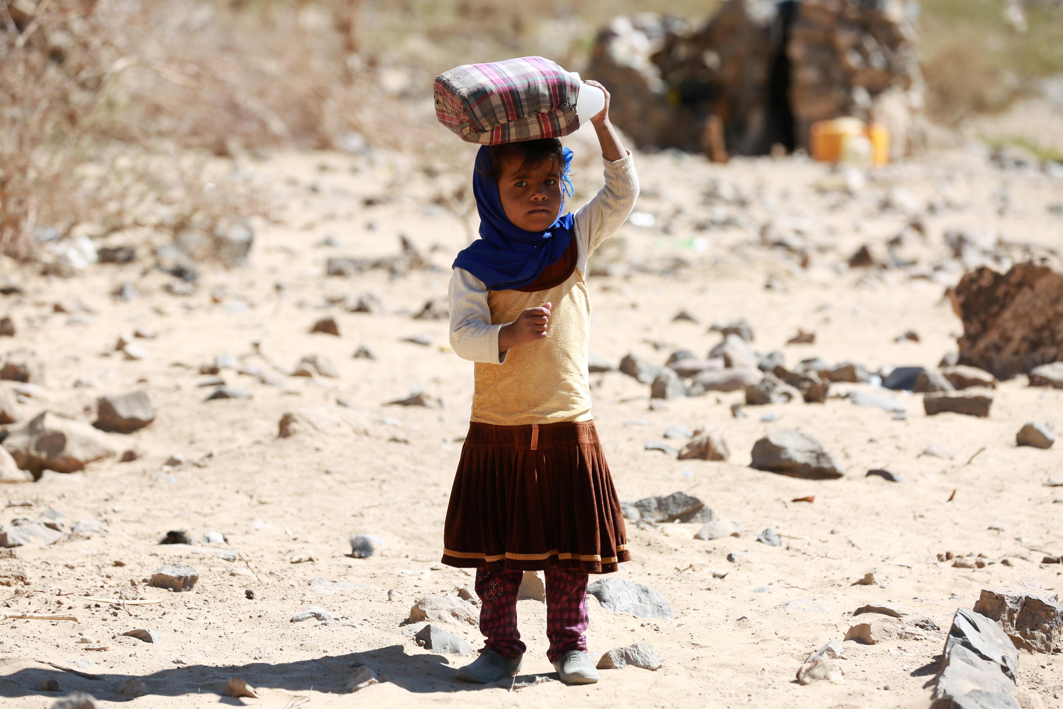 A displaced Yemeni girl carries a water gallon at a refugee camp located between Marib and Sanaa, Yemen March 29, 2018. Photo: Reuters