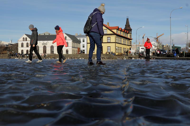 Tourists walk across water frozen into a ripple pattern on a pond in Reykjavik, Iceland, March 11, 2018. Picture taken March 11, 2018. Photo: Reuters