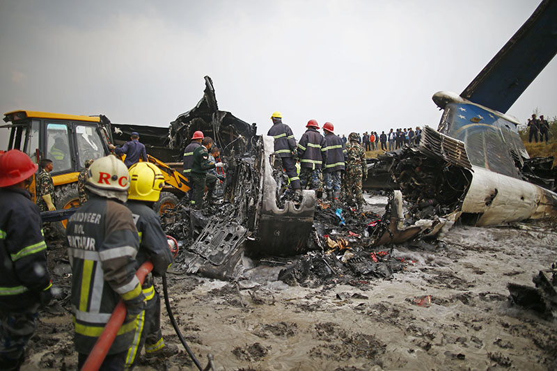 Fire fighters look on as bull dozer is used to recover bodies from the crashed aircraft of US-Bangla Airlines BS-211, in Tribhuvan International Airport, Kathmandu, on Monday, March 12, 2018. Photo: Skanda Gautam/THT