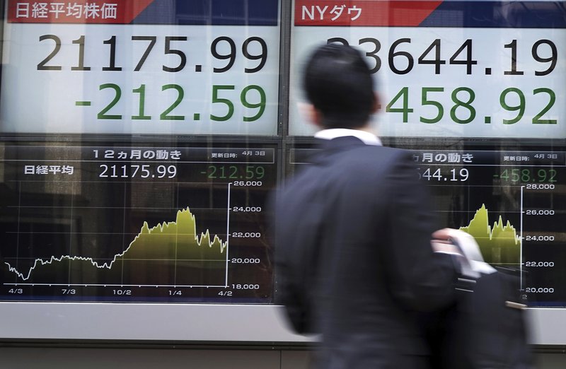 A man looks an electronic stock board showing Japanu2019s Nikkei 225 index and New York Dow index at a securities firm in Tokyo, on Tuesday, April 3, 2018. Photo: AP