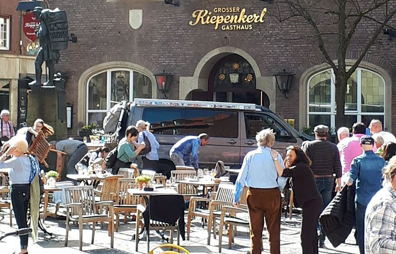 People stay in front of a restaurant after a vehicle crashed into a crowd killing four people and injuring 20 others in Muenster, Germany, on Saturday, April 7, 2018. Photo: AP
