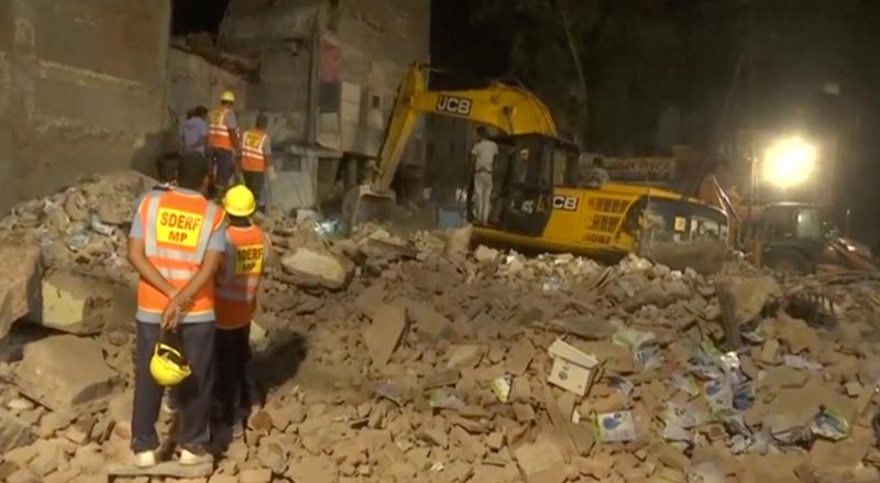 Workers watch as an excavator clears the debris at the site after a four-story hotel collapsed in a crowded part of the central Indian city of Indore late on Saturday, in this still image taken from video released on April 1, 2018. Photo: ANI via Reuters