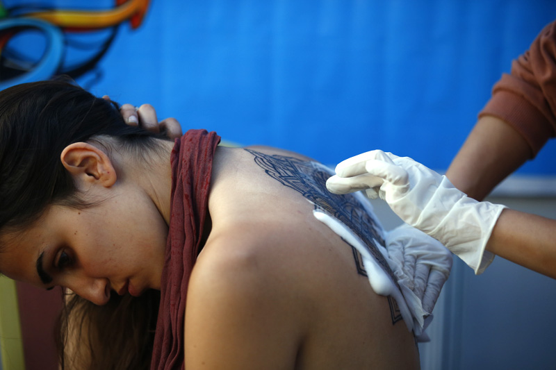 A woman gets a tattoo on her back during the International Nepal Tattoo Convention in Kathmandu, on Saturday, April 07, 2018. Photo: Skanda Gautam