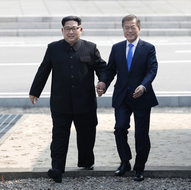 North Korean leader Kim Jong Un, left, and South Korean President Moon Jae-in cross the military demarcation line to the South side at the border village of Panmunjom in the Demilitarized Zone on Friday, April 27, 2018. Photo: AP