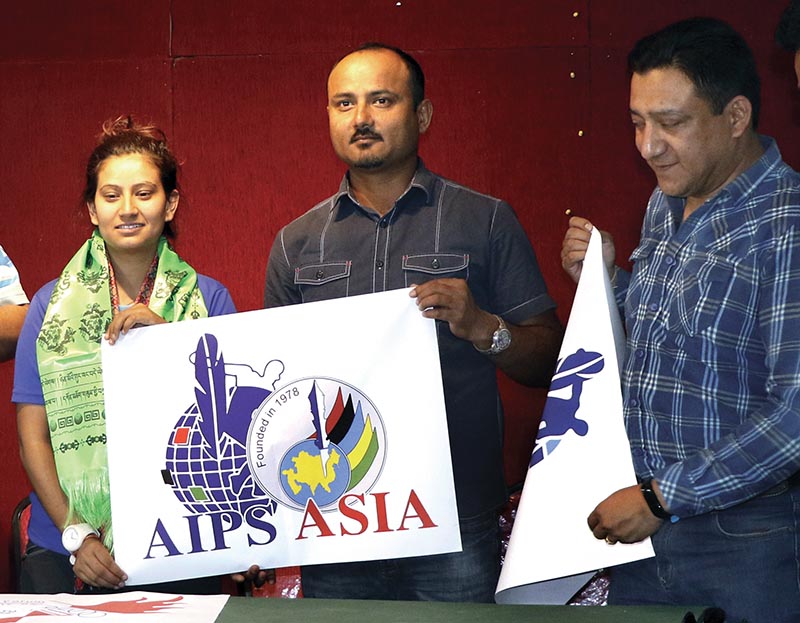 NSJF first Vice president Durga nath Subedi hands over AIPS-ASIA flag to Priya Laxmi Karki as Vice president  Sanjeeb Shilpakar (right) looks on during a programme in Kathmandu on Sunday. Photo: THT
