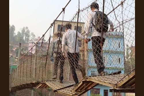 Students crossing a dilapidated suspension bridge on their way to school at Trivenichowk in Dhadingbensi, Dhading, on Tuesday, April 3, 2018. Photo: THT