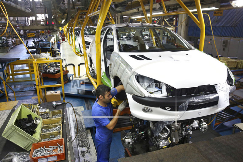 FILE - In this Oct. 11, 2014 file photo, an Iranian worker assembles a Peugeot 206 at the state-run Iran-Khodro automobile manufacturing plant near Tehran, Iran. From brand-new airplanes to oilfields, billions of dollars of deals stand on the line for international corporations as President Donald Trump weighs whether to pull America out of Iran's nuclear deal with world powers. (AP Photo/Ebrahim Noroozi, File)
