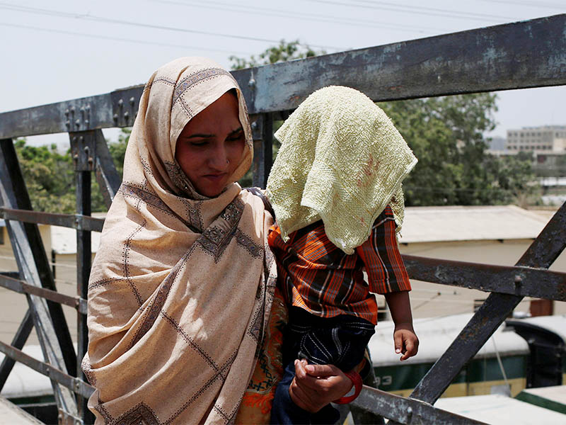A mother holds her child, covered with a towel to avoid sunlight, during a heatwave in Karachi, Pakistan May 21, 2018. Photo: Reuters