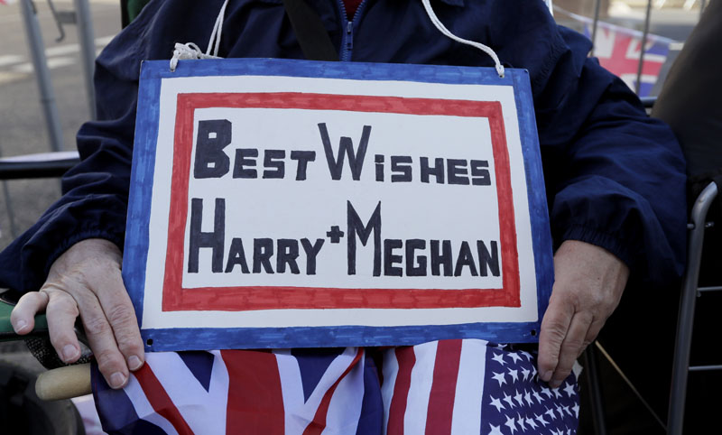 A well wisher holds a sign as she waits alongside Windsor Castle in Windsor, England, on Thursday, May 17, 2018.